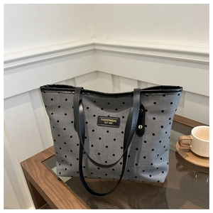 Detailed shot of retro polka dot tote bag with black leather logo and rivet accents
