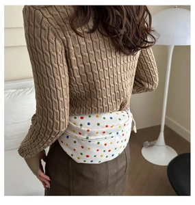 Detailed back view of a colorful polka dot crossbody bag worn over a beige knit sweater