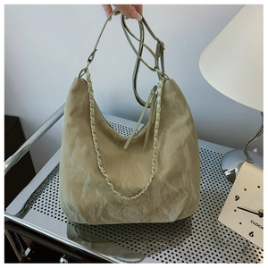 Detail of avocado green pleated shoulder bag showing textured fabric and metal chain strap