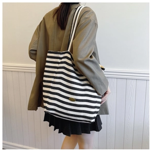 Detail of a large black and white striped tote bag with handmade leather patch detail