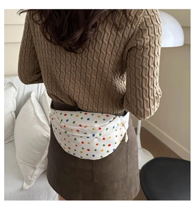 Close-up of stylish white canvas chest bag with vibrant colorful polka dots on a model