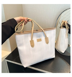 Detail view of large tote bag with cream wavy texture and elegant brown top handles