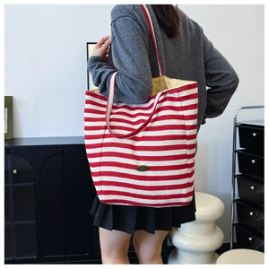 Detail view of large red and white striped canvas tote bag with Handmade tag on model