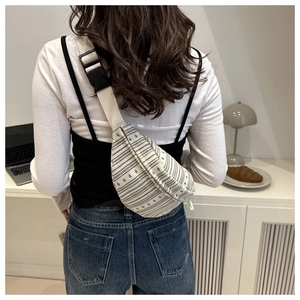 Detail of bohemian woven crossbody bag featuring floral patterns and adjustable buckle strap