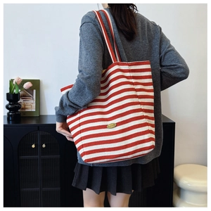 Detail of red and white striped canvas tote bag with vintage handmade metal plaque