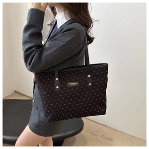 Detail of black tote bag with red heart pattern and stitched fashion logo label