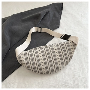 Close-up of woven geometric patterned crossbody bag with adjustable white canvas strap
