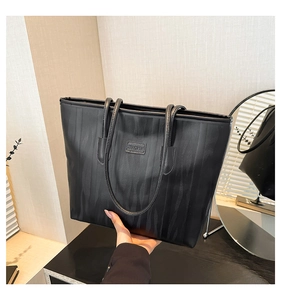 Detail of minimalist black tote bag featuring unique embossed fluid ripple textures
