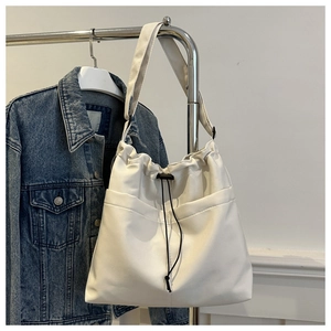 Detail of white Oxford tote featuring drawstring closure and symmetric front utility pockets