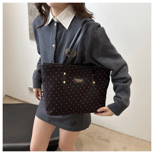 Détail du sac cabas noir à motifs de cœurs rouges avec plaque logo en métal doré