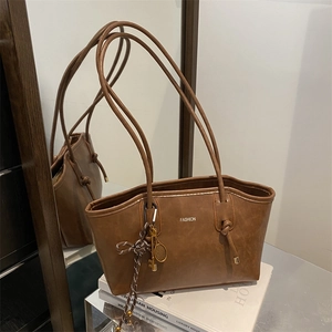 Brown vintage leather tote bag with long shoulder straps and tennis racket pendant