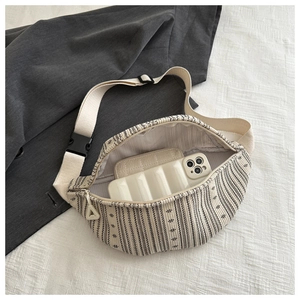Detail of striped woven chest bag featuring a wide nylon strap and spacious zip interior