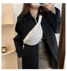 Detailed mirror selfie of white canvas crossbody bag featuring colorful polka dots and strap
