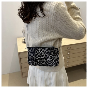 Detail of leopard print handbag with silver studs and chain strap on a model