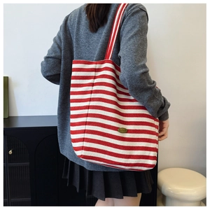 Detail of red and white striped canvas tote bag with handmade metal tag and sturdy strap