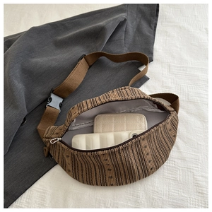 Close-up of striped woven crossbody bag showing spacious interior with plastic buckle
