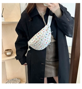 Close-up of stylish white crossbody waist bag with colorful polka dots and white zipper strap
