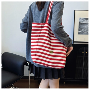 Detail of red and white striped canvas tote bag showing the handmade tag and large capacity