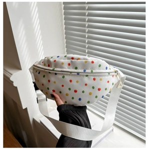 Close-up of white canvas waist bag with colorful polka dots and adjustable nylon strap
