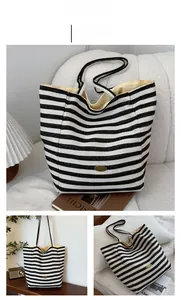Detail of striped canvas tote bag featuring a gold handmade plaque and soft yellow lining