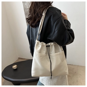 Detail of off-white oversized drawstring bucket bag with minimalist utility pockets