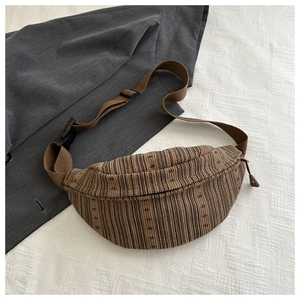 Detail of vintage striped crossbody chest bag with adjustable strap on grey blazer
