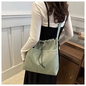 Detail of light green Oxford cloth tote bag showing drawstring closure and front pockets