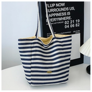 Close-up of blue and white striped canvas tote bag with gold handmade metal plaque