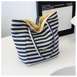 Detailed close-up of blue and white striped canvas tote bag with handmade metal plaque