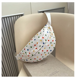 Detailed view of white crossbody chest bag with colorful polka dots on a stylish chair