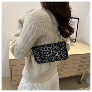 Close-up of leopard print baguette bag with silver metallic bead edges and chain strap