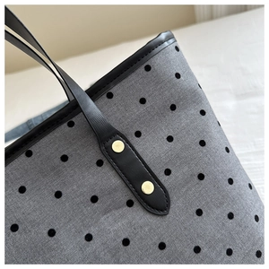 Detail of grey canvas tote with black flocking dots and metallic rivets for durability