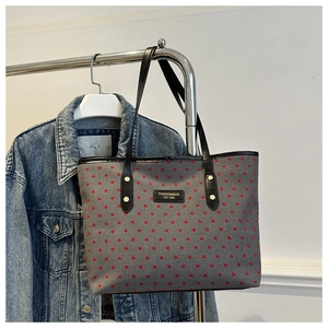 Détail du sac cabas gris avec motifs cœurs rouges et étiquette mode sur veste denim