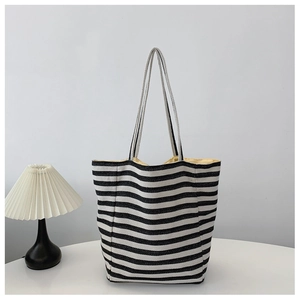Minimalist black and white striped canvas tote bag with long straps on a white table