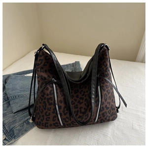 Dettaglio borsa shopper leopardata con doppie cerniere su sfondo bianco morbido