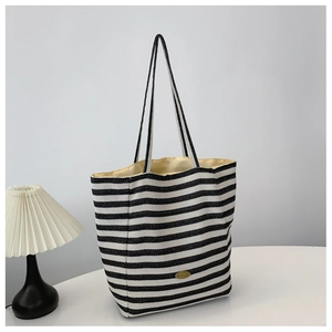 Minimalist black and white striped fabric tote bag with golden handmade metal logo detail