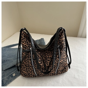 Dettaglio della borsa tote leopardata con manici in pelle nera e cerniere decorative
