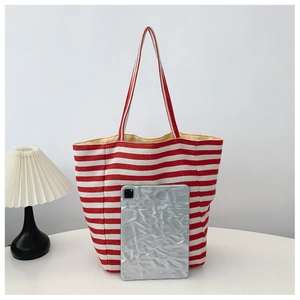 Detail of red striped canvas tote bag showing large capacity next to a tablet