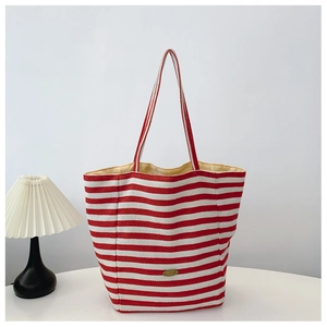 Detail of red and white striped canvas tote bag fabric with handmade metal logo tag