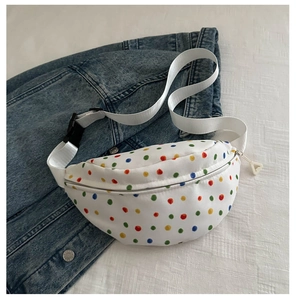 Detailed view of a white canvas waist bag with colorful polka dots on a denim jacket