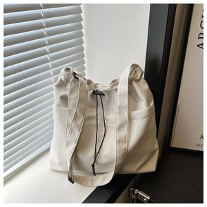 Close-up of a white nylon bucket bag with drawstring closure and side pocket detail
