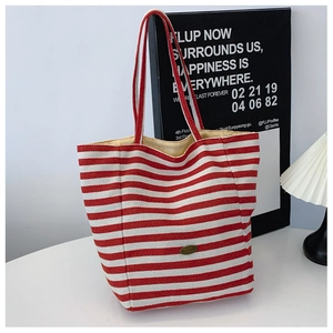 Close-up of red and white striped canvas tote bag with metal tag in a cozy home setting