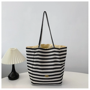 Close-up of handmade metal plaque on a black and white striped woven tote bag