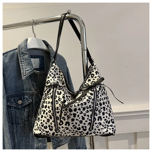 Détail du sac cabas en toile léopard avec fermetures éclair et nœud sur veste en jean
