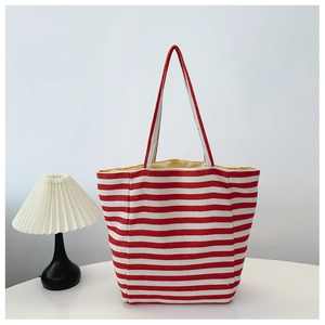 Detail of red and white striped canvas tote bag with slim shoulder straps on white desk