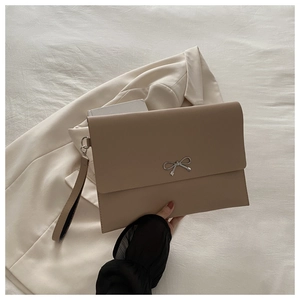 Detail view of khaki leather envelope clutch bag with silver bow and wrist strap