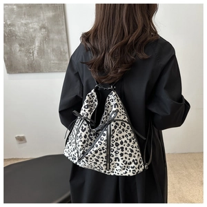 Close-up of leopard print shoulder bag with decorative black bow and metal zipper detail