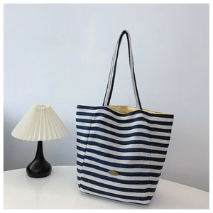Detail of blue and white striped canvas tote bag with oval handmade metal tag
