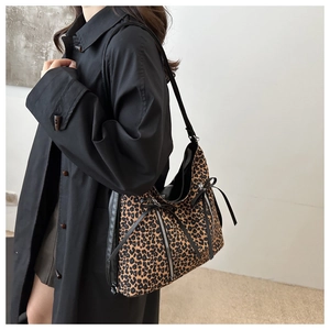 Detail of leopard print tote bag featuring vertical zippers and black ribbon bow accents