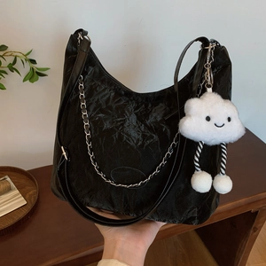 Large black crinkled tote bag with silver chain and white plush charm for daily commute
